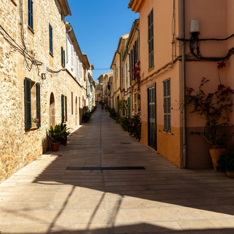 Sonnige Altstadtgasse mit typischen Steinhäusern in Porto Cristo an Mallorcas Ostküste